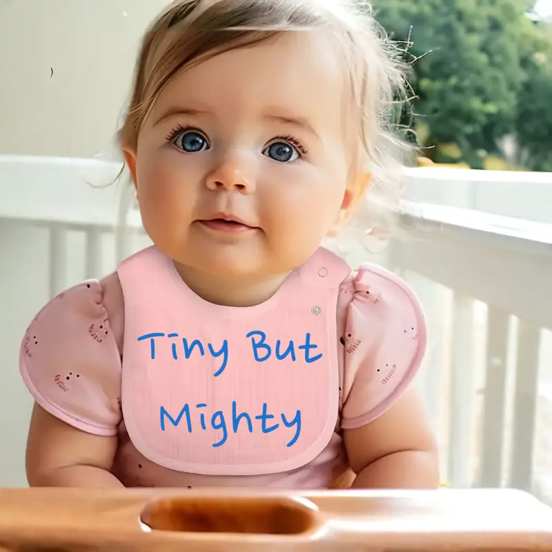 close up of a baby toddler wearing a comical saying bib, 'tiny but mighty